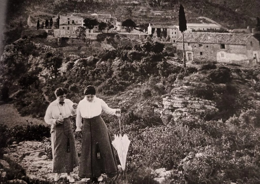 Vista panoràmica de dos dones amb l'antic Balneari de Cardó al fons. Imatge del Grup Aquí Tarragona